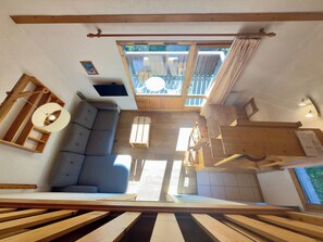 Una habitación amplia con un banco de madera integrado, un sofá y una mesa de comedor.