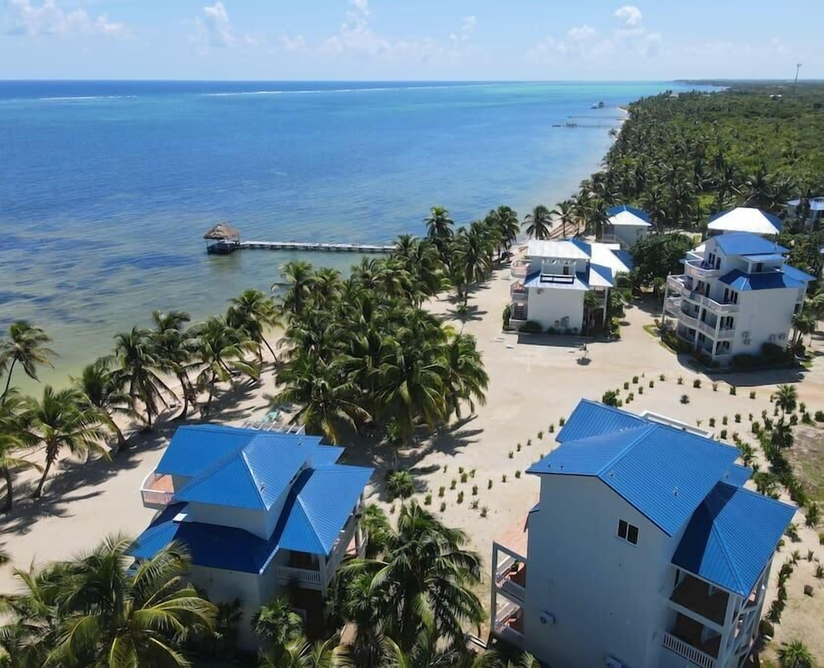 A resort with multiple buildings, a beach, and a pier.