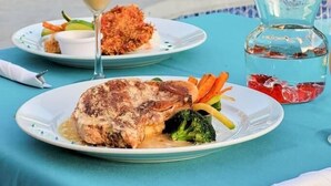 A dining table with plates of food, a martini glass, and a pitcher of water.