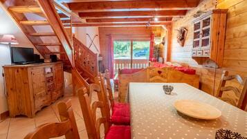 Ein gemütliches Holzhaus mit Essbereich, einer Treppe und einem Fernseher auf einem Schrank.