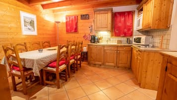 A wooden cabin interior with a dining area, kitchen, and a cozy atmosphere.