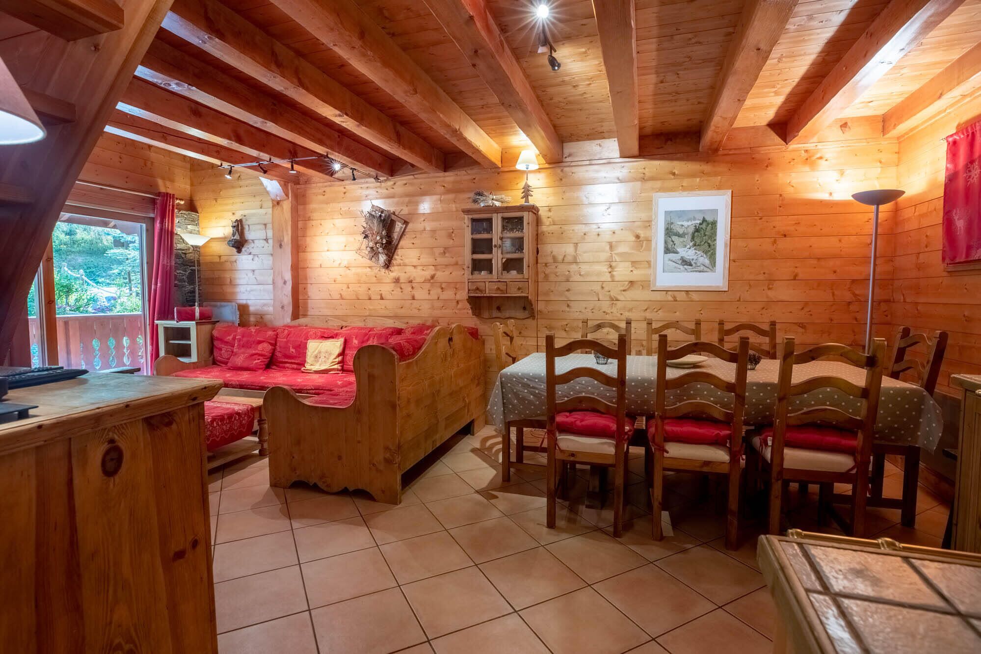Ein gemütliches Holzhaus-Interieur mit einer Couch, einem Esstisch, Stühlen und einer kleinen Kommode.
