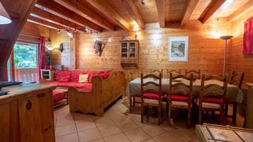 Ein gemütliches Holzhaus-Interieur mit einer Couch, einem Esstisch, Stühlen und einer kleinen Kommode.