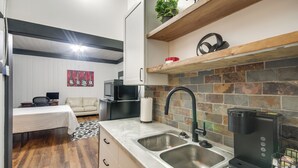 Una cocina compacta con un lavamanos doble, cafetera y microondas.