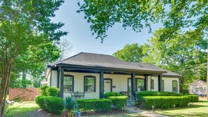 A single-story house with a front porch, a small front yard with trimmed bushes, and a visible mailbox. - Updated Cottage w/ Fireplaces in North Greenwood! (Greenwood)