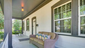 A covered porch with a wicker sofa, a dining table, and chairs. - Updated Cottage w/ Fireplaces in North Greenwood! (Greenwood)