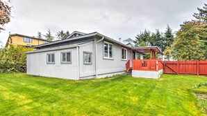 Une maison de plain-pied à l’extérieur gris, avec une terrasse rouge et une pelouse bien entretenue.