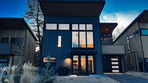 Una casa moderna de dos pisos con ventanas amplias, un garaje y un césped bien cuidado.