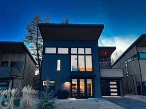 A modern two-story house with large windows, a garage, and a well-maintained lawn.