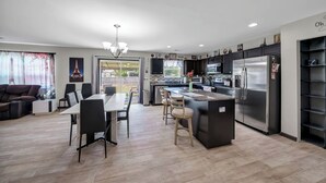 A modern kitchen with a central island, black cabinetry, and stainless steel appliances. - Home away from Home (Lexington)