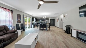 A modern living room with a brown leather sofa, a white coffee table, and a dining area with a kitchen in the background. - Home away from Home (Lexington)