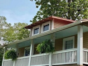 A two-story house with a porch, white railings, and a satellite dish. - The Firefly Cottage (Staunton)