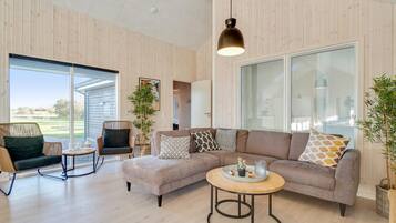 En moderne stue med en modulsofa, et rundt sofabord og en fletstol.