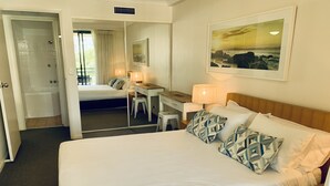 Ein Hotelzimmer mit einem großen Bett, einem Schreibtisch und einem Stuhl. Ein Badezimmer ist durch eine offene Tür sichtbar.