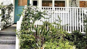 A house with a white porch, a green door, and a white picket fence. - Charming Southern Cottage (Savannah)
