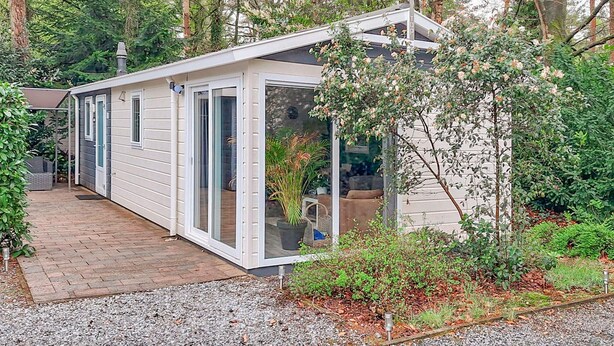 Een modern, gelijkvloers huis met een overdekte patio en een glazen deur naar een gezellig interieur.