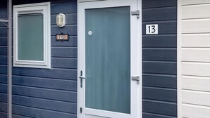 Een huis met een witte deur en een raam. Er is een bord met de tekst 'Yver' en het nummer '13' op de muur.