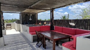 An outdoor patio with a wooden table and red cushioned seating. - Cozy 2BR Apt, 50 meters from the beach with large pool (Progreso)