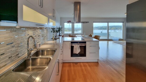 A modern kitchen with a central island, stainless steel appliances, and a view of a bridge and water.