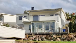 A two-story house with a glass conservatory, a stone foundation, and a metal roof.
