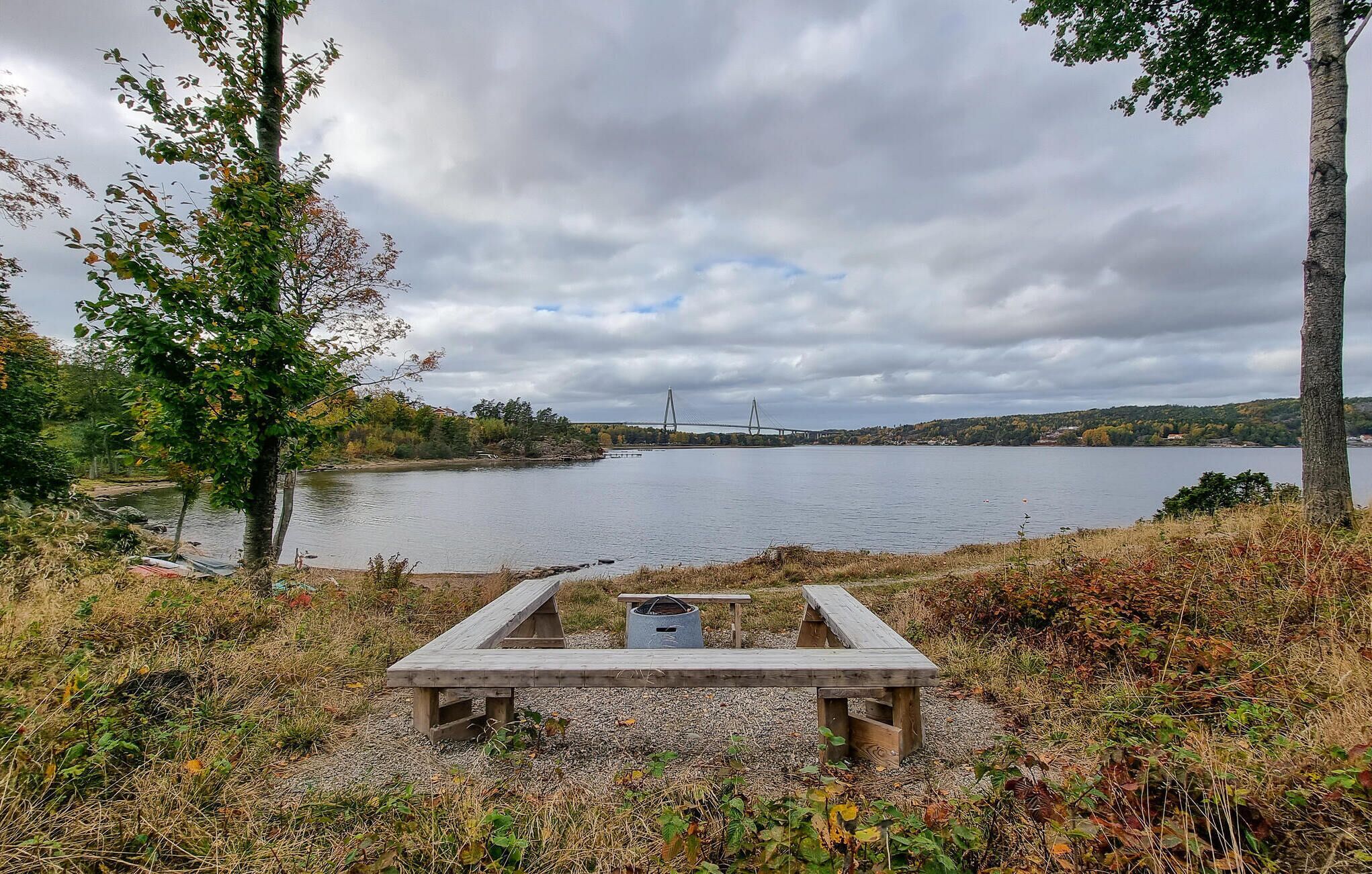 A lakeside view with a wooden bench and a small structure, likely a restroom, in the foreground.