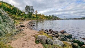 A sandy beach with large rocks and a forested area in the background.