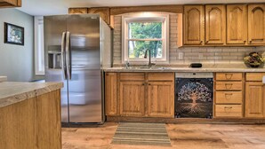 A modern kitchen with wooden cabinets, a stainless steel refrigerator, a dishwasher, and a window with a view of trees. - Centrally Located Mount Pleasant Retreat! (Mt Pleasant)