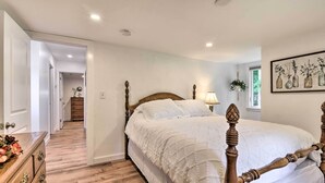 A bedroom with a wooden bed frame, a white bedspread, a wooden dresser, and a hallway leading to another room. - Centrally Located Mount Pleasant Retreat! (Mt Pleasant)