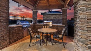 Une terrasse extérieure avec un mur en pierre, une table ronde et des chaises en métal.