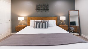 A neatly arranged bedroom with a large bed, two bedside tables with lamps, a wall-mounted light fixture, and a mirror. - NEW! Near ASU/Spring Training/Old Town Scottsdale! (Tempe)