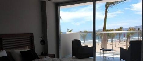 A bedroom with a large window overlooking a beach.