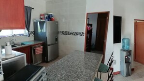 Una cocina compacta con encimera de granito, electrodomésticos de acero inoxidable y dispensador de agua.