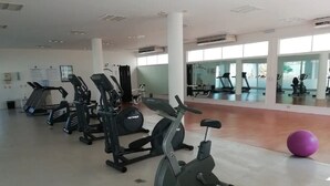 Un gimnasio con diversos equipos de ejercicio, incluyendo cintas de correr, bicicletas estáticas y máquinas elípticas.