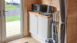 A compact kitchen with a microwave, kettle, and toaster on a wooden countertop. - Lavender is a cosy pod on the site of the Centry Touring Park in Brixham. (Brixham)