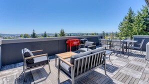Une terrasse sur le toit, aménagée avec du mobilier d’extérieur, un barbecue et offrant une vue sur la ville.