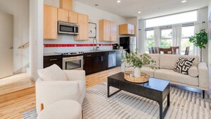 Une cuisine moderne avec des meubles de couleur sombre, un four à micro-ondes et une cuisinière. On y trouve également un coin repas avec un canapé et une table basse.
