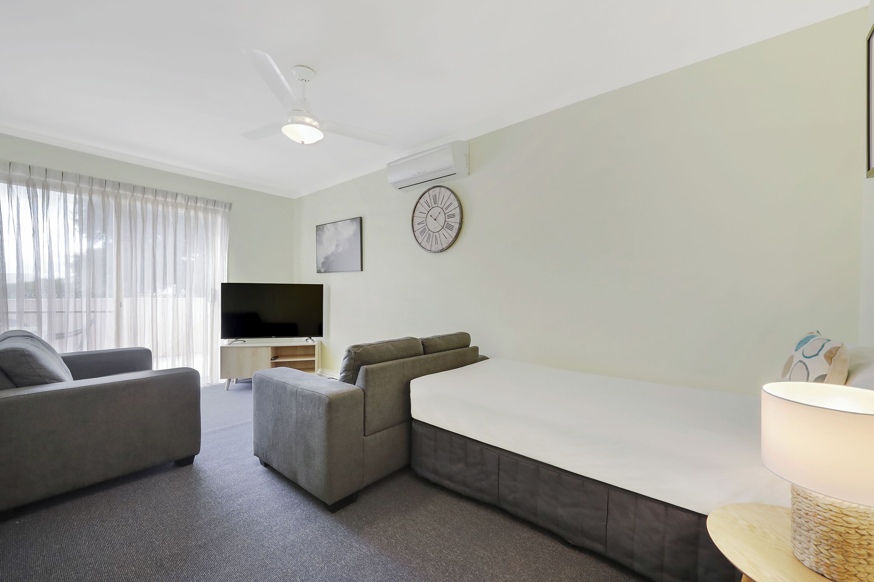 A modern living room with a sofa, a TV, and a flat-screen TV on a stand.