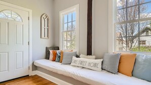 A cozy room with a built-in bench, a large window, and a door. - 717 Woodward · Historic Southern Belle - Walk to Hot Spots! (Atlanta)
