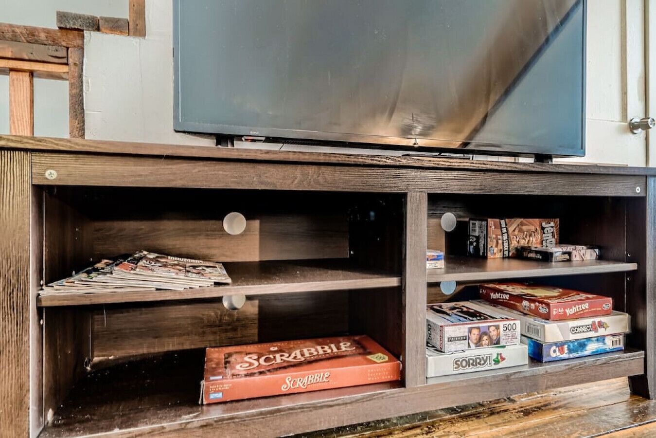 A wooden entertainment unit with shelves holding board games and magazines.