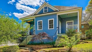 A two-story house with a porch, a small garden, and a clear blue sky. - 717 Woodward · Historic Southern Belle - Walk to Hot Spots! (Atlanta)