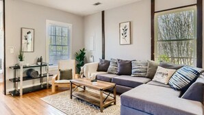 A modern living room with a sofa, coffee table, and a plant. - 717 Woodward · Historic Southern Belle - Walk to Hot Spots! (Atlanta)