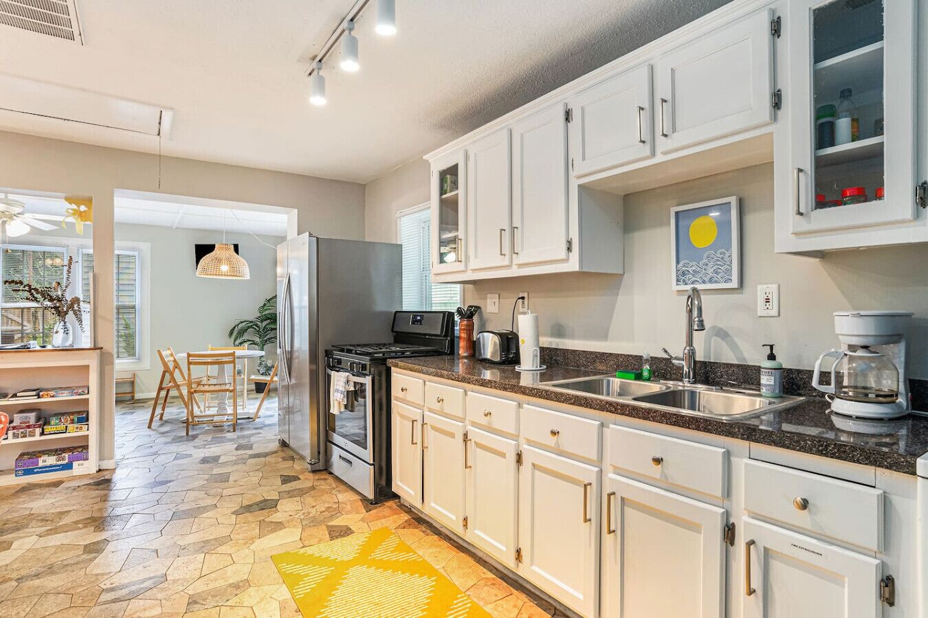 A modern kitchen with white cabinets, a granite countertop, a built-in oven, and a coffee maker.