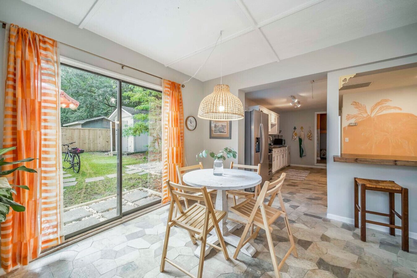 Een moderne keuken met een eethoek, grote ramen en uitzicht op de achtertuin.