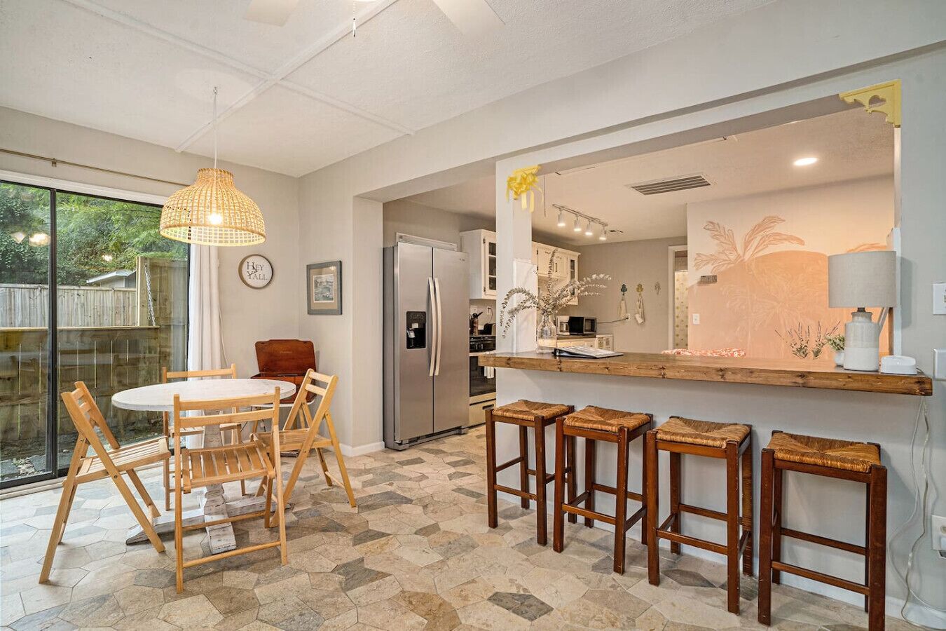 Une cuisine moderne dotée d’un îlot central, d’un coin repas avec une table ronde et des chaises, et d’un bar avec des tabourets.