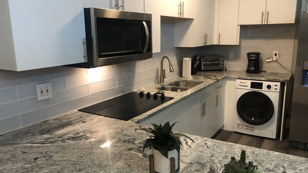 Una cocina moderna con microondas integrado, pileta y lavavajillas.