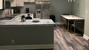 Una cocina moderna con una isla central, electrodomésticos integrados y un comedor con mesa y sillas.