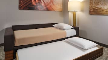 A hotel room with a double bed, a bedside lamp, and two large abstract paintings on the walls.
