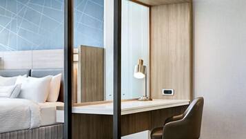A modern hotel room with a large bed, a desk, and a mirror.