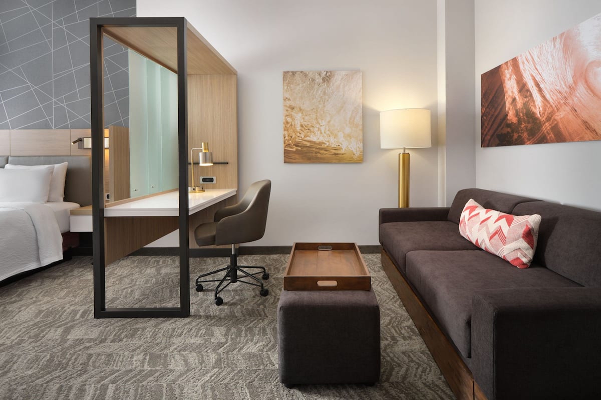 Ein Hotelzimmer mit Bett, Schreibtisch, Stuhl, Sofa und Couchtisch.
