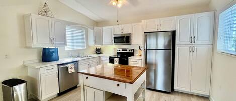 A modern kitchen with white cabinets, stainless steel appliances, and a wooden island.